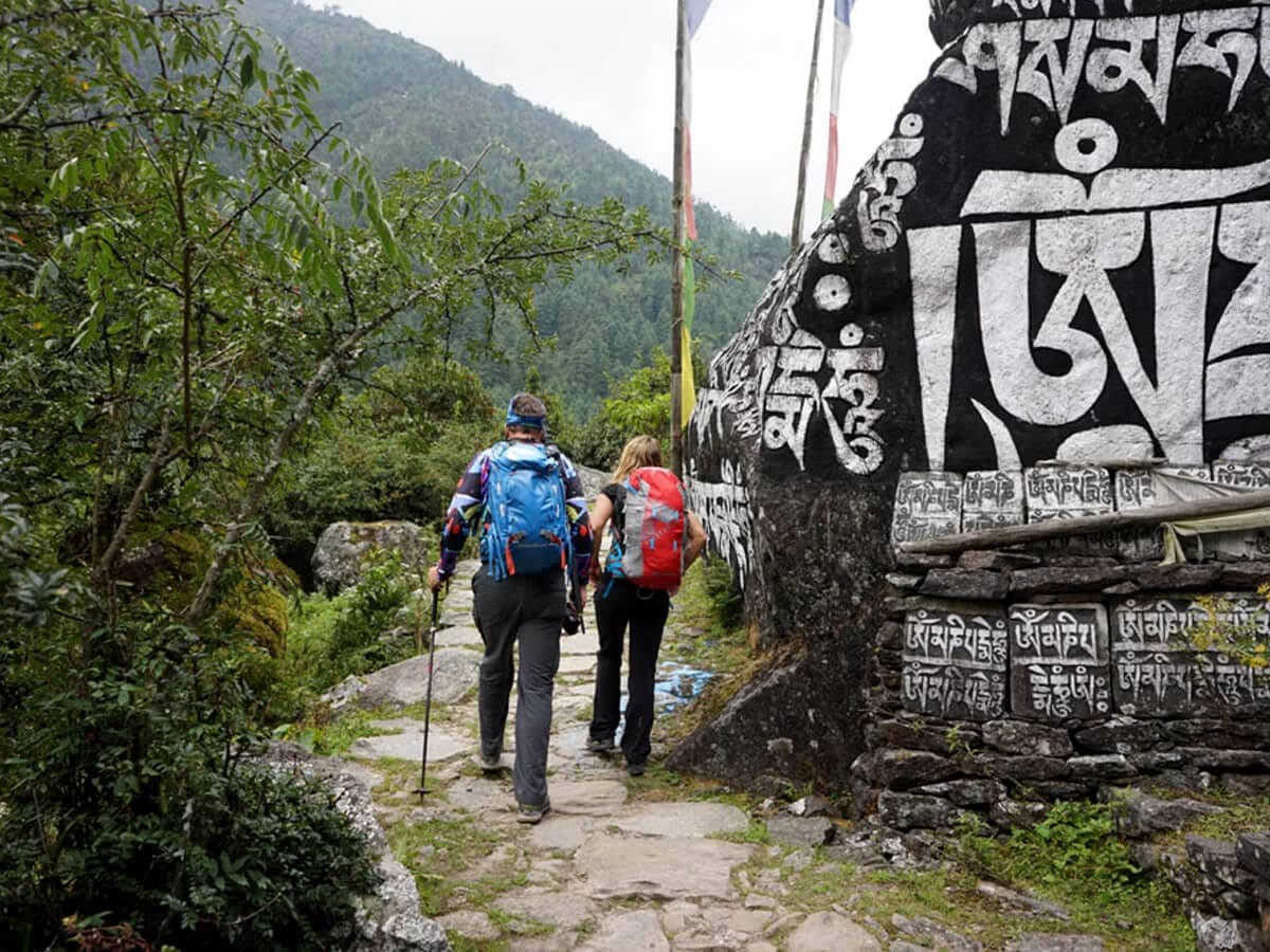 Trekkers walk by prayers engraved rock